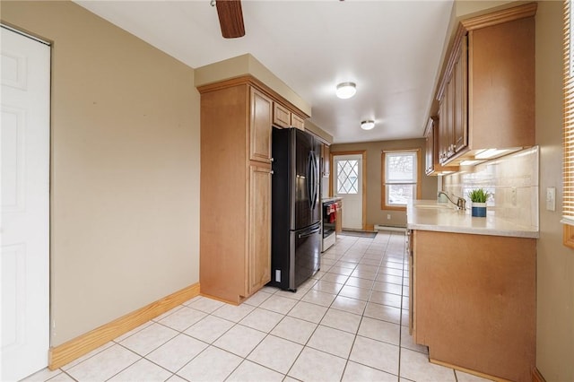 kitchen featuring light countertops, light tile patterned floors, baseboards, backsplash, and freestanding refrigerator