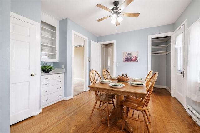 dining room featuring baseboards, ceiling fan, a baseboard heating unit, and light wood finished floors