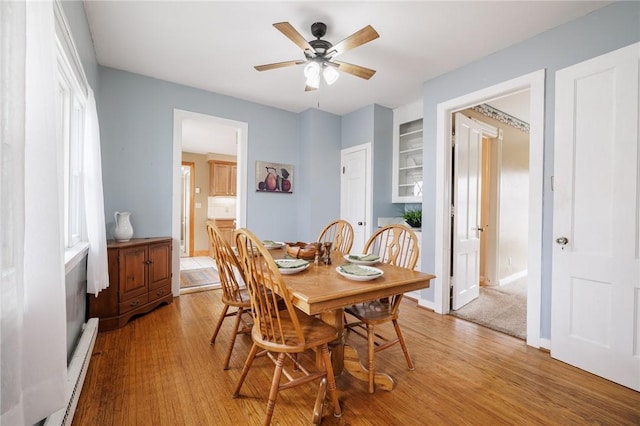 dining area featuring baseboards, light wood-style floors, and a ceiling fan
