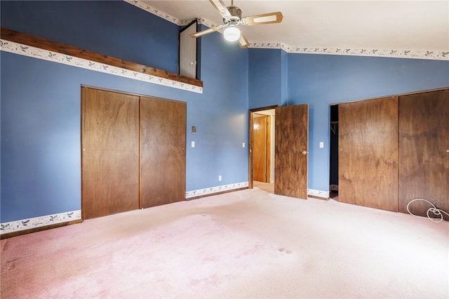 unfurnished bedroom featuring a closet, high vaulted ceiling, carpet flooring, baseboards, and ceiling fan