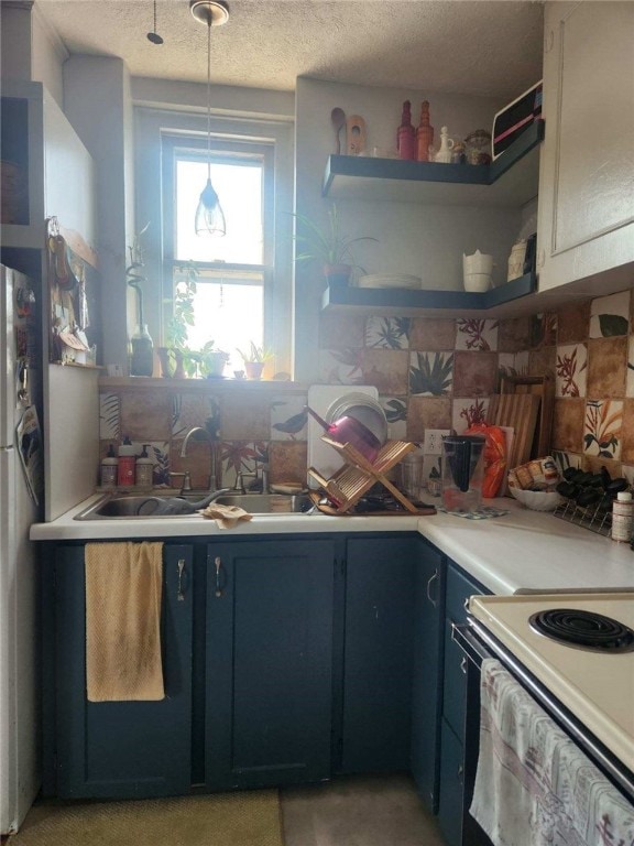 kitchen featuring blue cabinetry, light countertops, open shelves, a textured ceiling, and a sink