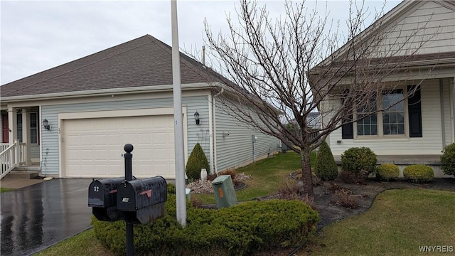 view of side of property featuring a shingled roof, a garage, and aphalt driveway