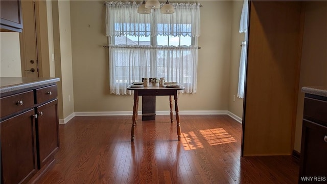 dining space featuring baseboards and dark wood-style flooring