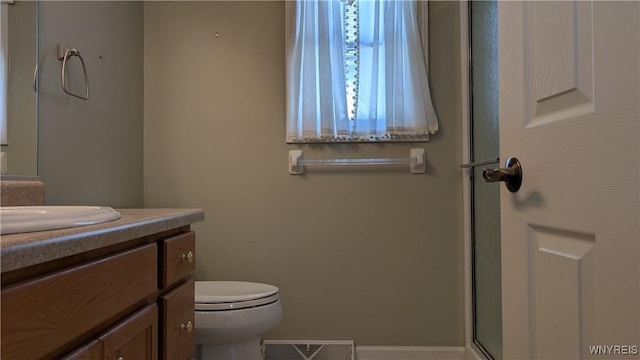 full bath featuring toilet, vanity, an enclosed shower, and visible vents