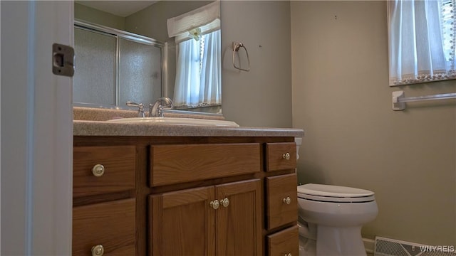 bathroom with a stall shower, visible vents, toilet, and vanity