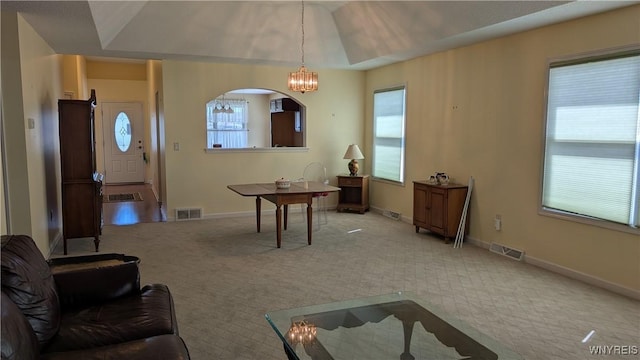 carpeted dining area featuring baseboards, visible vents, and an inviting chandelier