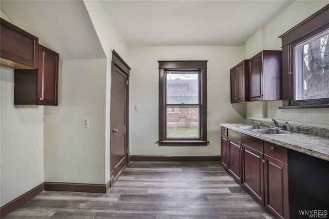 clothes washing area featuring a sink, dark wood-type flooring, and baseboards