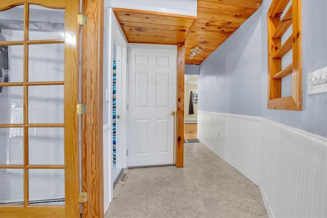 corridor featuring a wainscoted wall, tile patterned flooring, wood ceiling, and a baseboard radiator