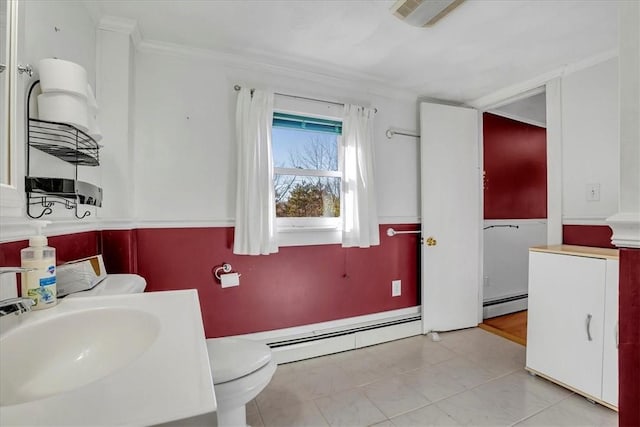 bathroom featuring tile patterned floors, crown molding, a baseboard heating unit, and a sink