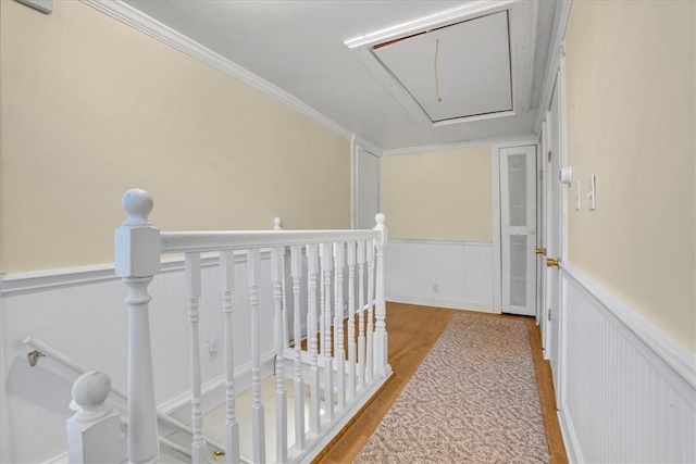 corridor featuring a wainscoted wall, an upstairs landing, wood finished floors, and attic access
