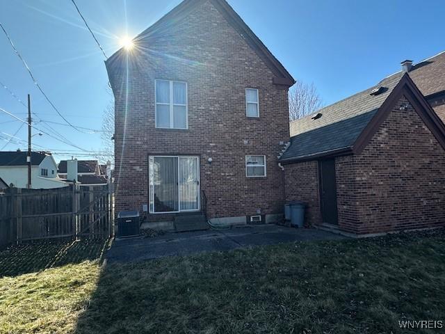 back of property featuring a lawn, fence, and brick siding