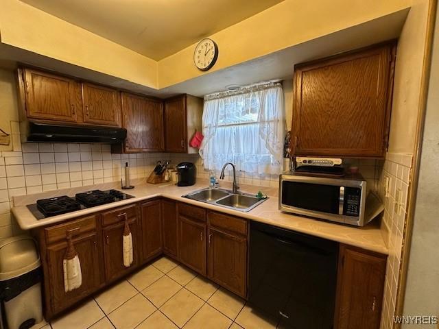 kitchen featuring a sink, under cabinet range hood, light countertops, and black appliances