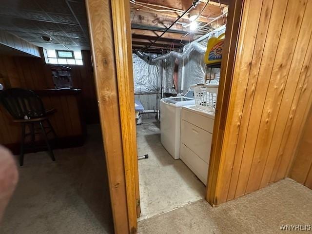 basement featuring a bar, washer and clothes dryer, and wooden walls
