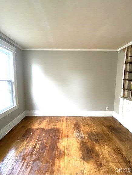 spare room with ornamental molding, hardwood / wood-style flooring, and baseboards