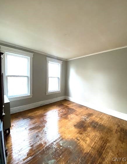 empty room with baseboards, ornamental molding, and wood-type flooring