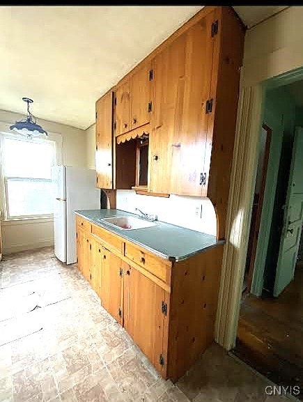 kitchen with brown cabinets, a sink, and freestanding refrigerator