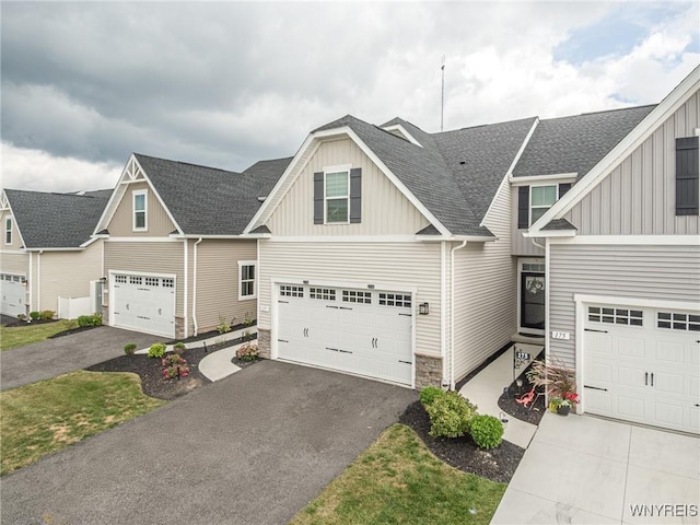 craftsman-style home featuring stone siding, board and batten siding, driveway, a garage, and a shingled roof