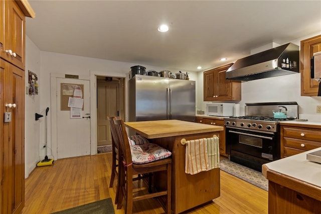4508 State Route 64, Bristol, NY 14424 - kitchen featuring a kitchen bar, wooden counters, light wood-style floors, wall chimney range hood, and appliances with stainless steel finishes