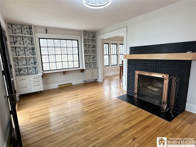 3514 Lake St, Ellicott, NY 14701 - living area featuring a textured ceiling, baseboards, a fireplace, and light wood-type flooring