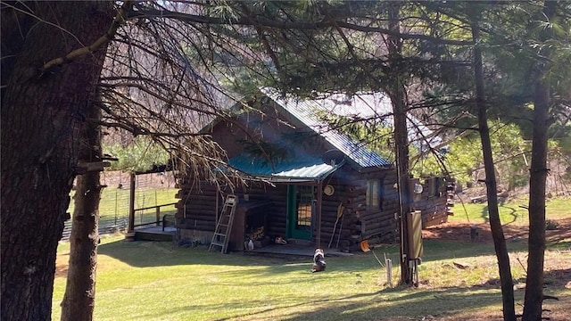 view of side of property featuring a yard, log siding, and metal roof