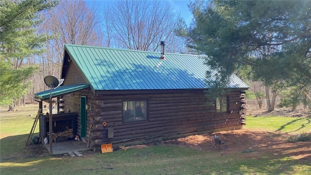 view of property exterior with a lawn, log exterior, and metal roof
