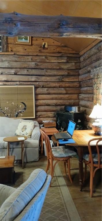 sitting room featuring log walls, wood finished floors, and beamed ceiling