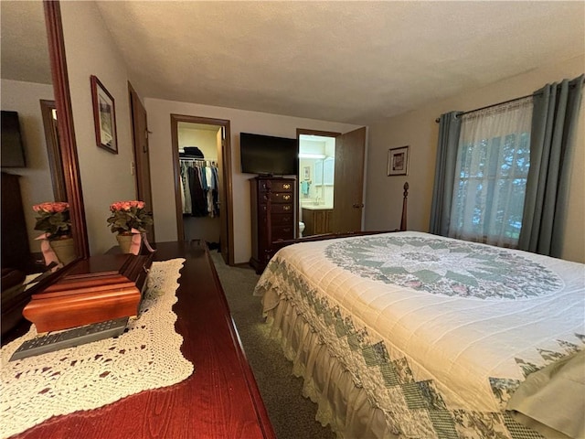 carpeted bedroom featuring a walk in closet, a closet, ensuite bathroom, and a textured ceiling