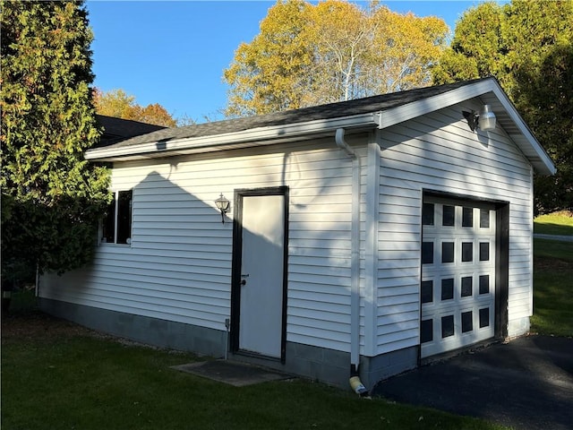 view of home's exterior featuring an outdoor structure, roof with shingles, and a detached garage