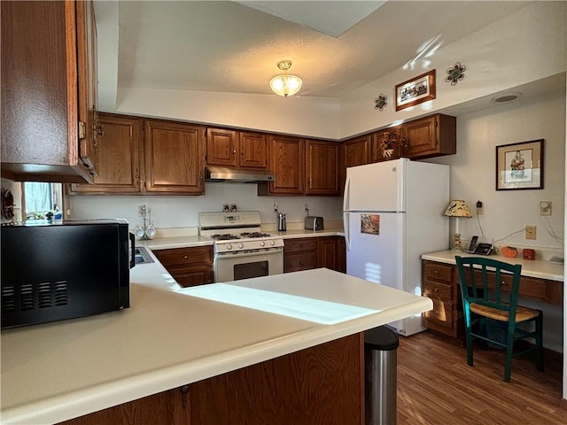 kitchen with light countertops, a peninsula, white appliances, dark wood finished floors, and under cabinet range hood