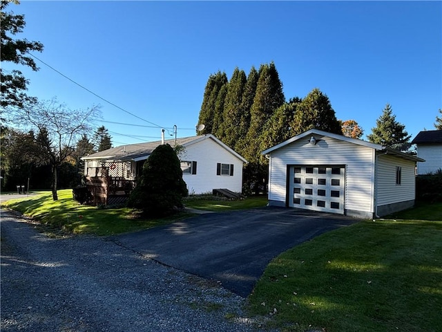 view of side of home with a lawn, aphalt driveway, a garage, and an outdoor structure