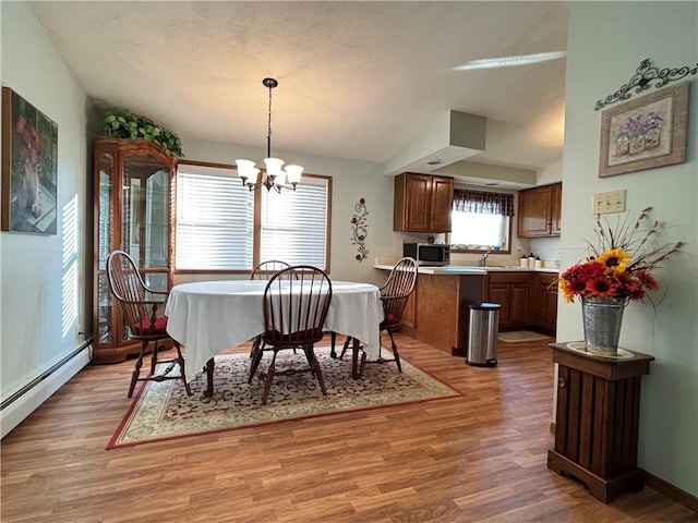 dining area featuring a textured ceiling, an inviting chandelier, light wood-type flooring, and a baseboard radiator