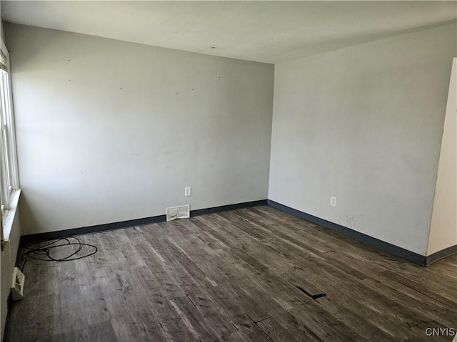 spare room featuring baseboards, visible vents, and dark wood-style floors