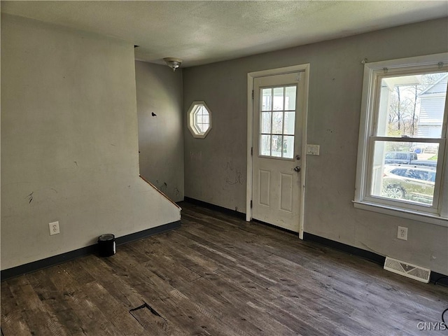 entryway featuring dark wood finished floors, baseboards, visible vents, and plenty of natural light