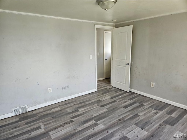spare room featuring baseboards, crown molding, wood finished floors, and visible vents