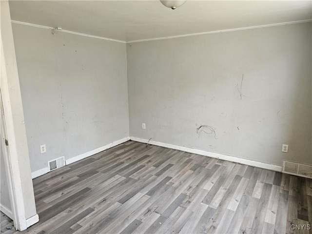 unfurnished room with wood finished floors, visible vents, and crown molding