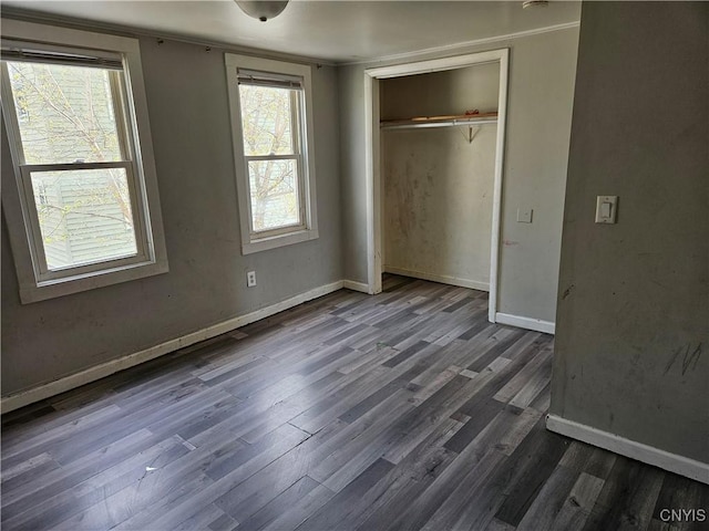 unfurnished bedroom featuring baseboards, a closet, dark wood-style floors, and multiple windows