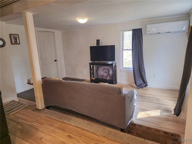 living area with baseboards, a fireplace, a wall mounted air conditioner, and light wood-style floors