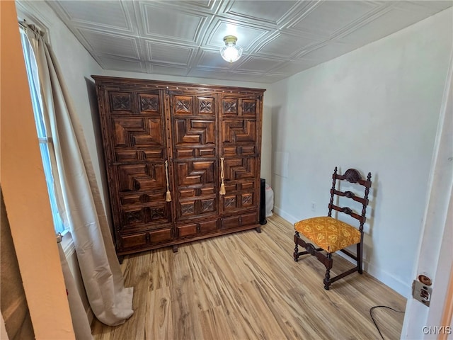 living area featuring an ornate ceiling, light wood-style floors, and baseboards