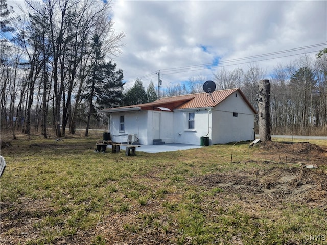 rear view of property with stucco siding, a yard, and a patio