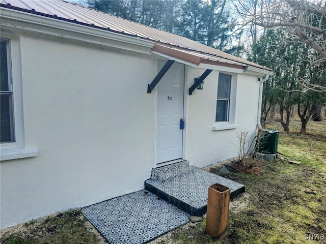 view of exterior entry featuring stucco siding and metal roof