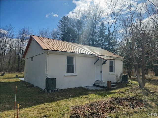 exterior space with a front yard, stucco siding, and metal roof