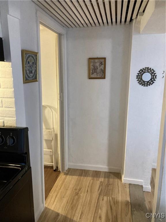 hall featuring baseboards, light wood-style floors, and washer / dryer