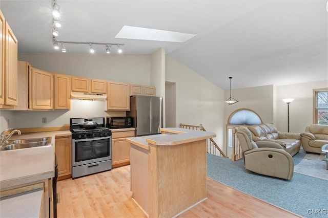 kitchen with a sink, appliances with stainless steel finishes, open floor plan, under cabinet range hood, and light brown cabinets