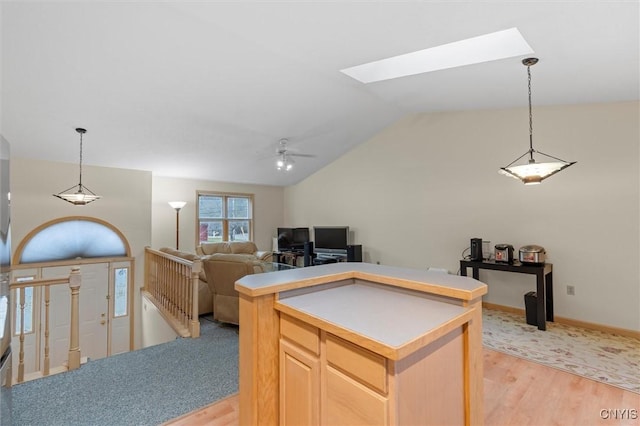 kitchen with open floor plan, light wood-type flooring, vaulted ceiling with skylight, a ceiling fan, and light brown cabinets