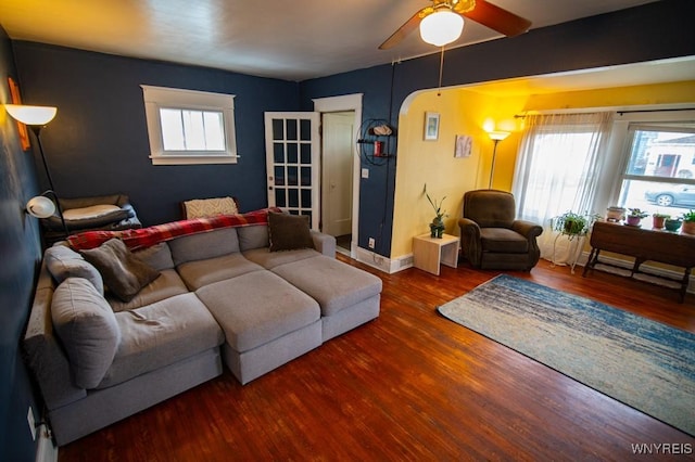 living area with arched walkways, wood finished floors, baseboards, and ceiling fan