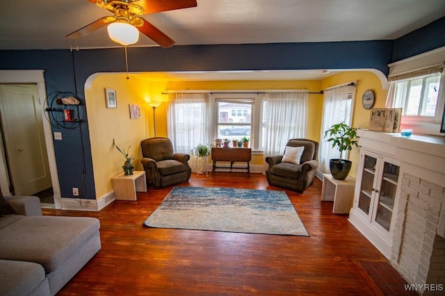 living room with baseboards, wood finished floors, arched walkways, and ceiling fan