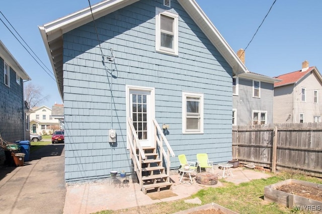 rear view of house with a garden, fence, and entry steps