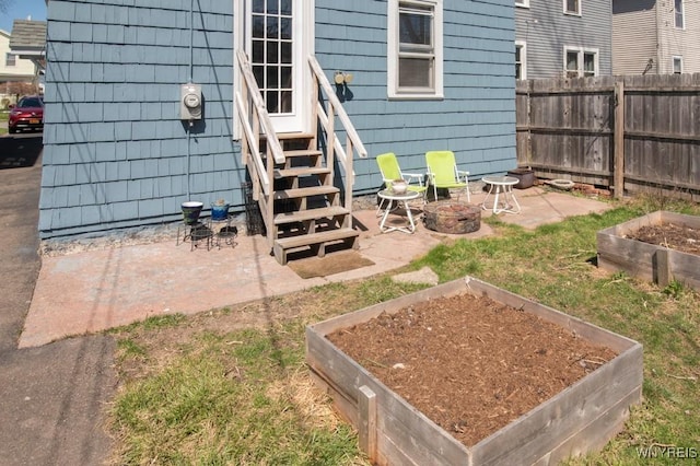 view of yard with a garden, fence, a patio area, entry steps, and an outdoor fire pit