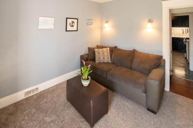 carpeted living area with baseboards and visible vents