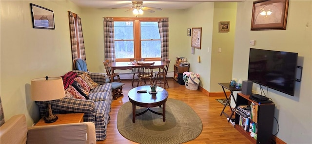 living area featuring baseboards, a baseboard radiator, light wood-style floors, and ceiling fan